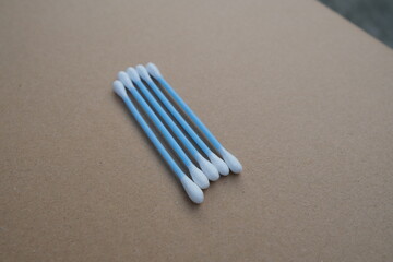 A group of cotton swabs arranged in a row on a light brown surface
