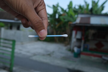 A single cotton swab held in a hand