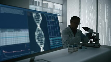 Male scientist in a lab coat working in a futuristic science laboratory with a microscope. Computer display showing the human DNA helix - Powered by Adobe