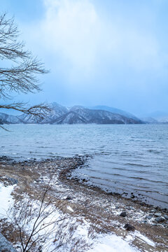 Lake Chuzenji, on the mountains in Nikko, Japan, during winter season with snow fall under cloudy sky and very cold weather. Japanese letters were name of public gate in Japanese faith.