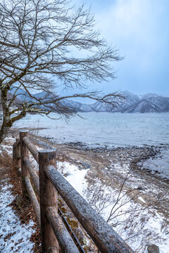 Lake Chuzenji, on the mountains in Nikko, Japan, during winter season with snow fall under cloudy sky and very cold weather. Japanese letters were name of public gate in Japanese faith.