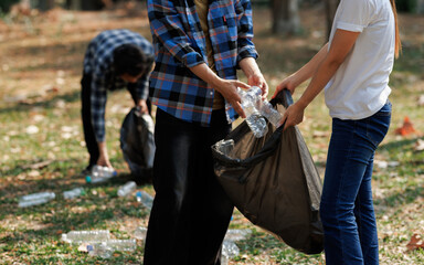 A group of environmental conservation volunteers is helping each other collect trash in a public park.