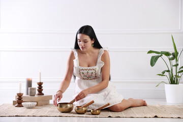Woman with singing bowls on floor indoors