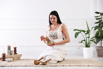Woman with singing bowls on floor indoors