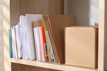Different paper envelopes and parcel on wooden shelf in post office, closeup