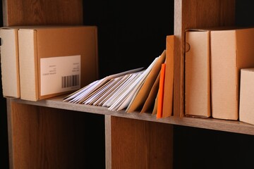 Different paper envelopes and parcels on wooden shelves in post office