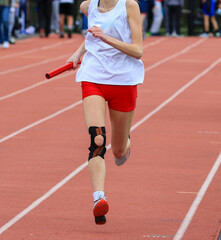 Relay Runner in Motion on Track During Athletic Competition Wearing a Knee Brace