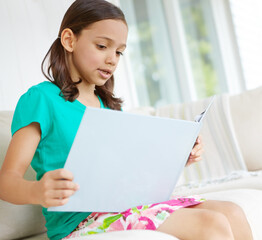 Book, child or girl on sofa for reading, learning and language development with education in...