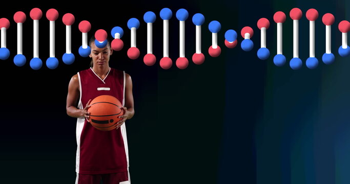 Image of dna strand over female basketball player holding ball