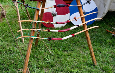A close up on a simple wooden frame used to hold numerous bows and crossbows together with arrows and shields seen during a shooting contest during a medieval fair in Poland