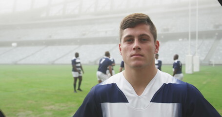 Portrait image of a rugby player in a stadium with the team in the background