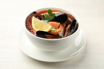 Delicious seafood soup in bowl on light wooden table, closeup