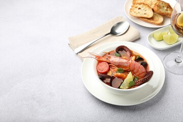 Tasty seafood soup served on light grey table, space for text