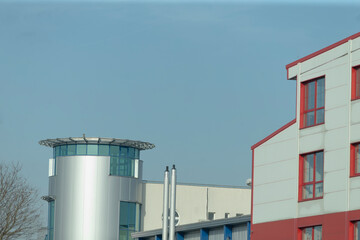 A striking red and white building stands tall, featuring an impressive tower in the background that enhances the overall urban landscape