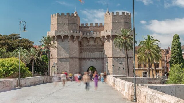 Serrans Towers (Torres de Serranos) timelapse hyperlapse in Valencia, Spain. A grand medieval gate from the city's ancient walls. Bustling street scene under a blue sky frames this historic landmark