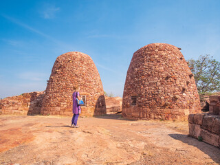 Woman exploring ancient temple site at Badami. Tourist walking among ruins stone walls gateways in Karnataka, India