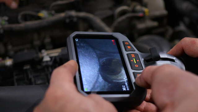 The mechanics at the auto service use an endoscope and examine the inside of the engine