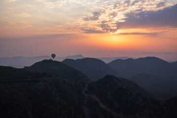 Hot air balloon seen at sunrise soaring over a mountains in the Jaipur outskirts, Rajasthan, India