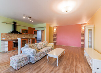 Modern apartment living room with open kitchen and floral sofa.