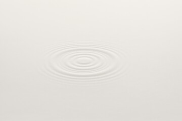 Obraz premium Concentric ripples expanding on the surface of a pristine white liquid create a mesmerizing and calming pattern, evoking feelings of tranquility and purity in a minimalist design