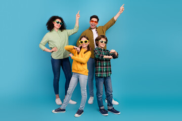 Fototapeta premium Happy young family posing playfully against blue background, expressing joy and togetherness with stylish outfits and gestures
