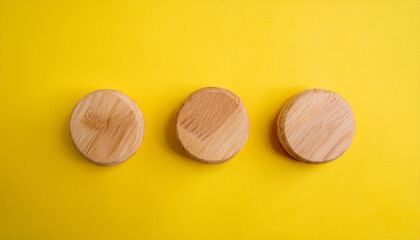 Obraz premium Three wooden discs on yellow surface. Minimalist composition. Wood circles. Flat lay.