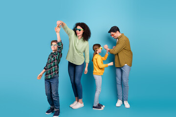 Joyful family dancing together in vibrant casual outfits on a colorful background, expressing harmony and happiness during a leisure moment
