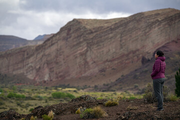 Woman appreciating amazing sandstone landscape with big red cliffs. Los Altares, Chubut, Rio Negro