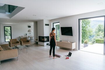 Young Beautiful Female Exercising, Stretching and Practising Yoga with Trainer via Video Call...