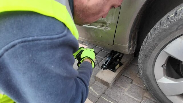 A guy changes tire on street to summer tire in nature