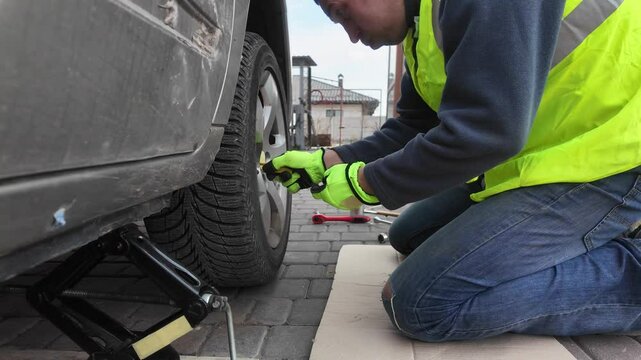 A guy changes tire on street to summer tire in nature