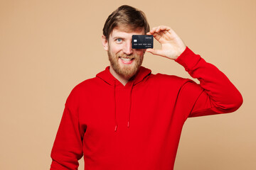 Young Caucasian man he wear red hoodie casual clothes hold in hand cover eye face with mock up of...