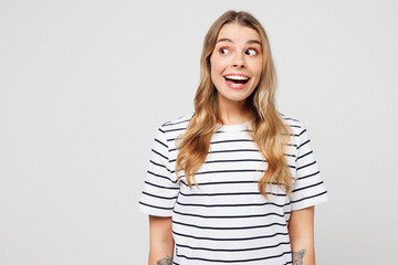 Fototapeta premium Young happy shocked surprised excited amazed fun woman she wears striped t-shirt casual clothes look aside on area mock up isolated on plain solid white background studio portrait. Lifestyle concept.