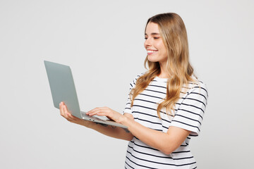 Young smart smiling happy IT woman wear striped t-shirt casual clothes hold use work on laptop pc...