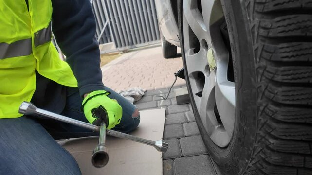 A guy changes tire on street to summer tire in nature