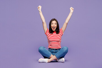 Full body young Caucasian woman she wears red striped t-shirt casual clothes sit do winner gesture looking camera isolated on plain pastel light purple background studio portrait. Lifestyle concept. © ViDi Studio