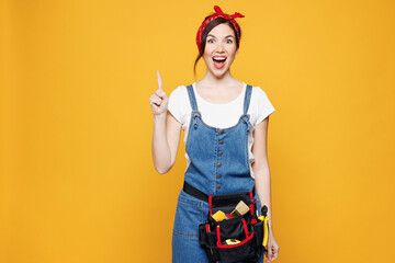 Young employee laborer handyman woman wear overalls belt hold index finger up with great new idea...