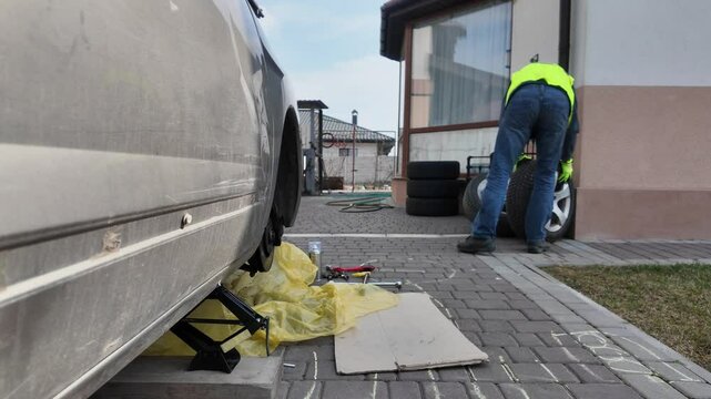 A guy changes tire on street to summer tire in nature
