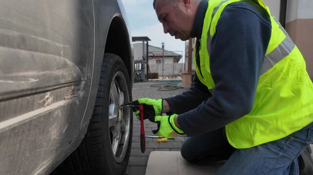 A guy changes tire on street to summer tire in nature