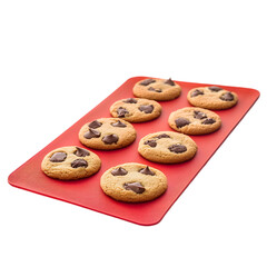 Eight chocolate chip cookies arranged on a red textured baking sheet