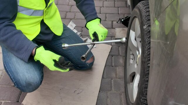 A guy changes tire on street to summer tire in nature