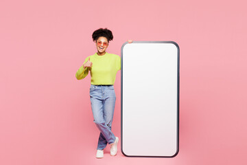 Full body young woman she wear green sweater casual clothes big huge blank screen mobile cell phone smartphone with workspace area show thumb up isolated on plain pink background. Lifestyle concept.