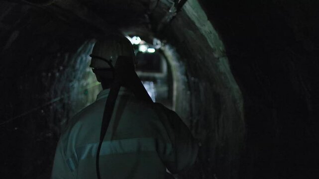 miner walks in tunnel with pickaxe on his shoulder
