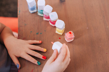 little girl paints her nails with different colors