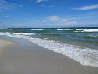 Wide Angle View of Pristine Sandy Beach with Rolling Waves and Clear Blue Sky at Empty Shoreline