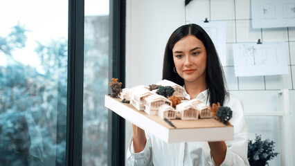 Close up of skilled young beautiful caucasian architect lift house model left side and right sight...