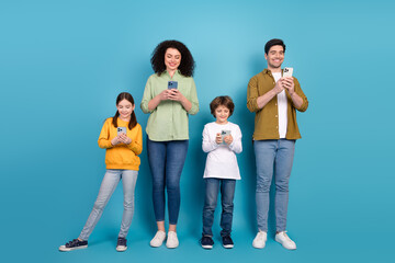 Fototapeta premium Happy family enjoying a day using smartphones against a bright blue background with each member engaged in meaningful activities