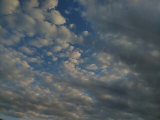 Obraz premium Dramatic Cloudy Sky with Blue Patches and White Fluffy Clouds Creating Abstract Natural Pattern at Sunset