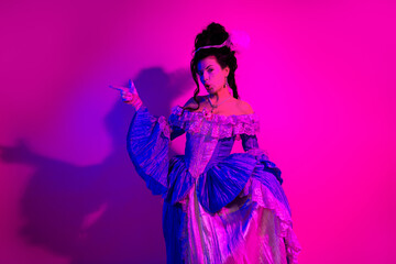 Elegant woman in royal costume posing with style on a colorful neon background