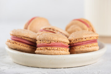 Vegan homemade caramel macarons with raspberry cream on shea butter with cup of tea, closeup. Sugar, lactose and gluten free.